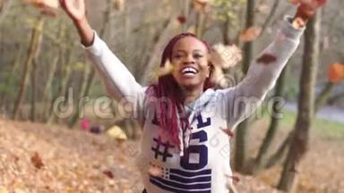 这位美丽的非洲裔美国妇女<strong>正在</strong>秋天的公园<strong>里</strong>玩得很开心。 那个女孩<strong>正在</strong>扔黄叶子。